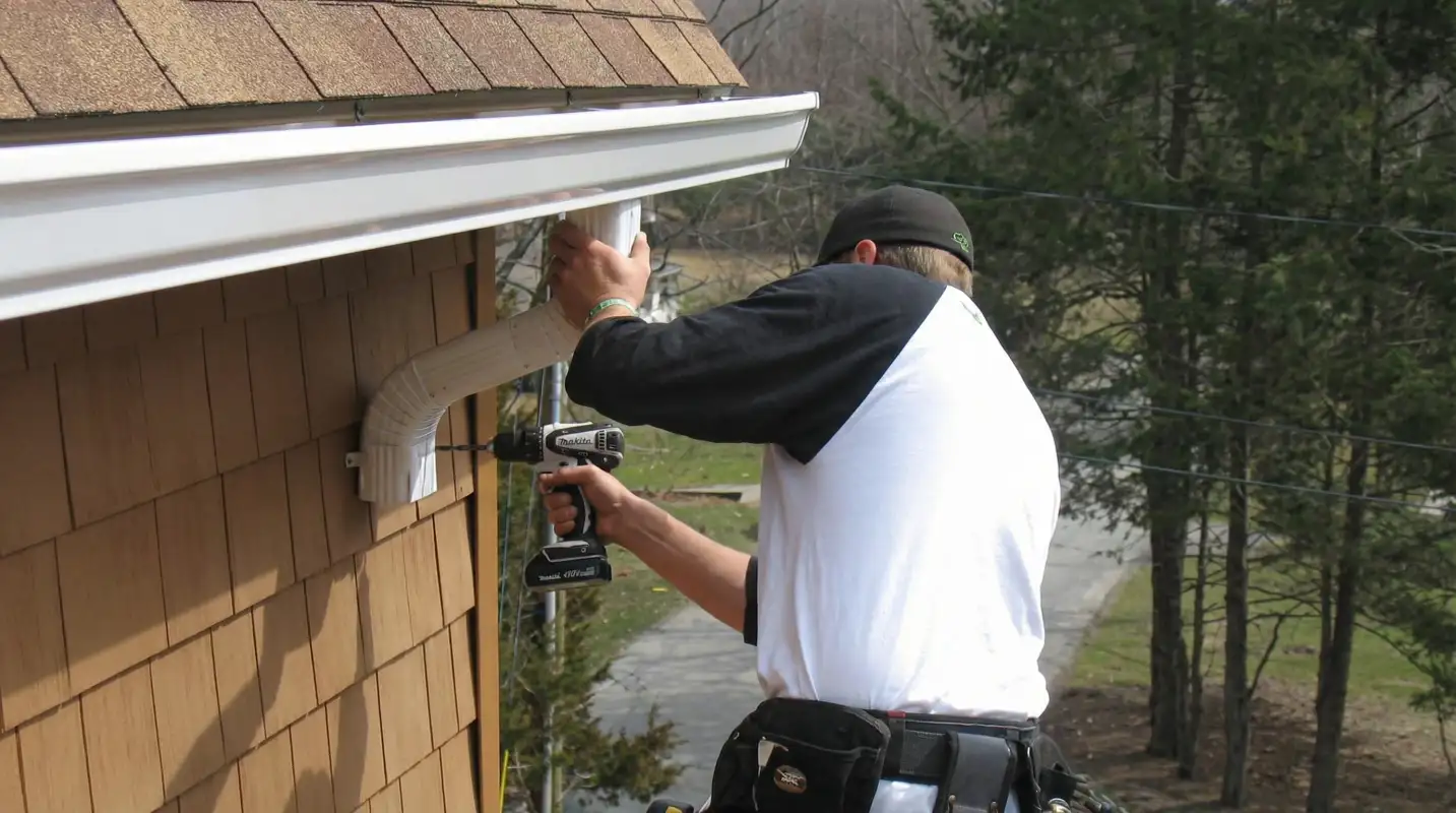 Professional contractor installing tan vinyl siding panels on a residential home exterior in Worcester, MA
